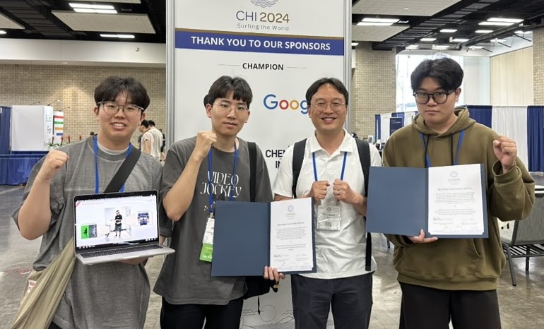 Group photo holding a laptop and documents at CHI 2024.