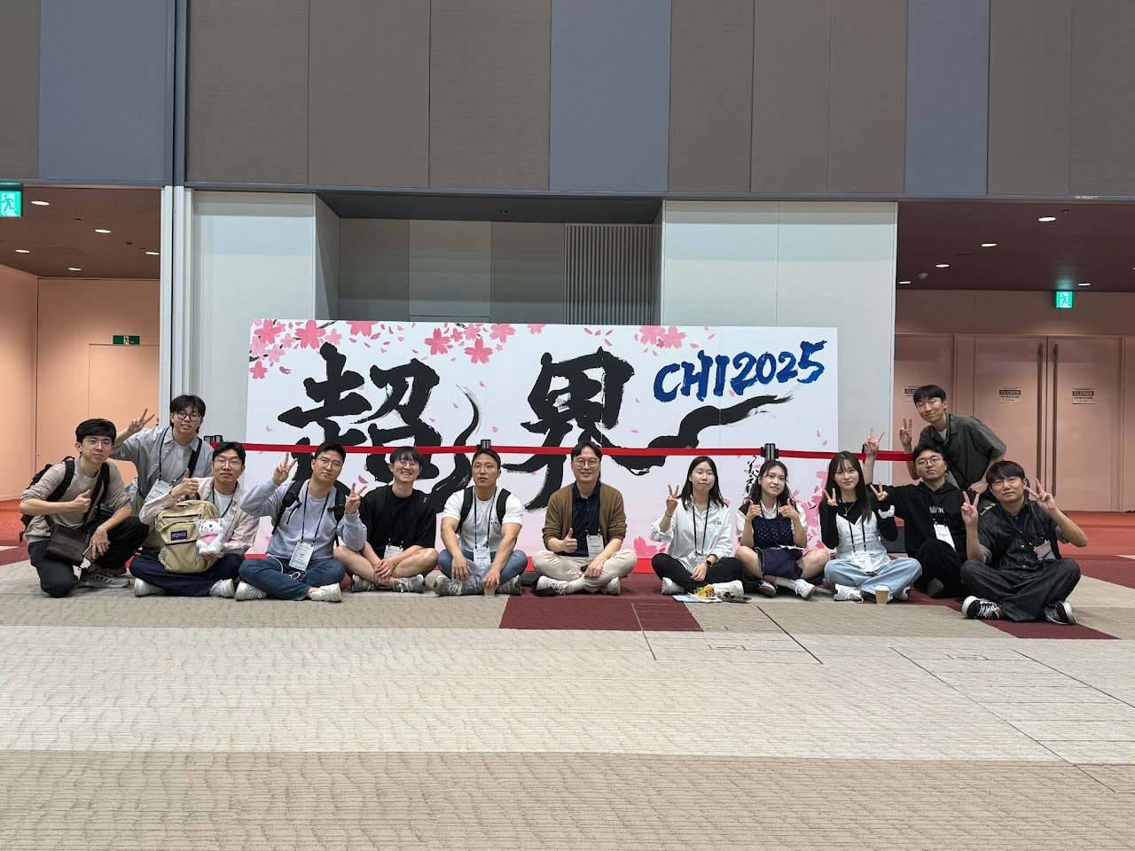 Group photo in front of the CHI 2025 conference display.