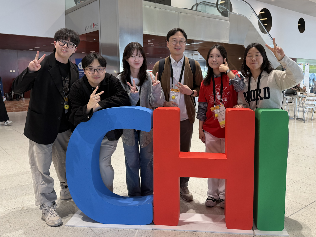 Group photo beside the CHI letters at CHI 2026.