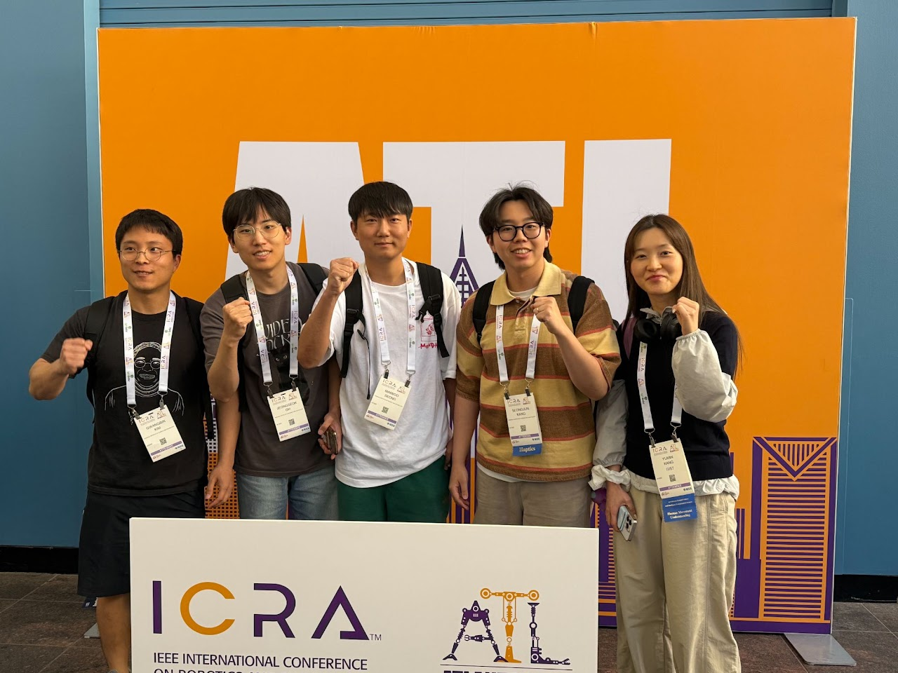 Group photo in front of the ICRA 2025 conference display.