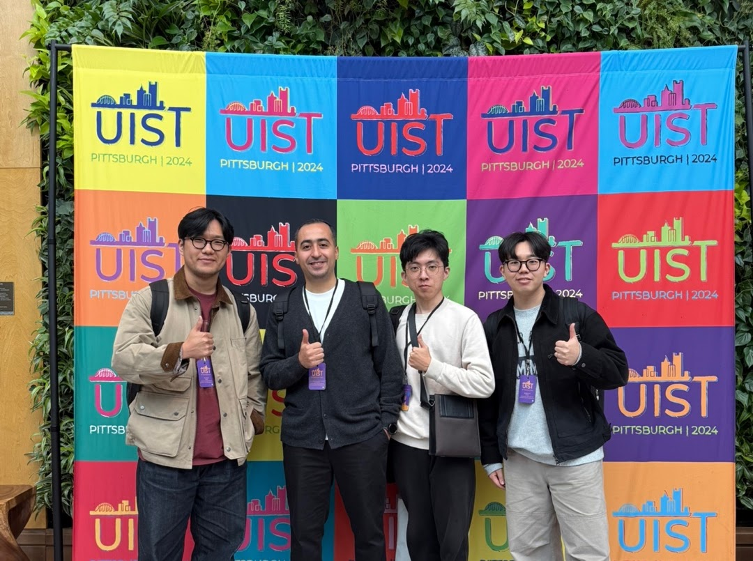 Group photo in front of the UIST 2024 conference display.